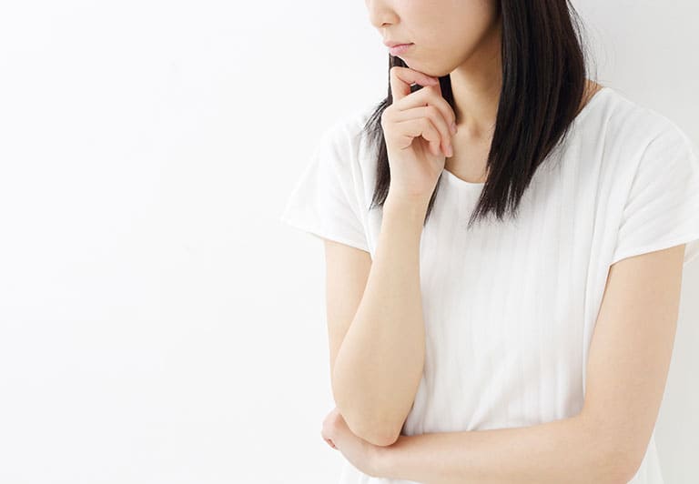 顎に手をあて、考えている様子の女性