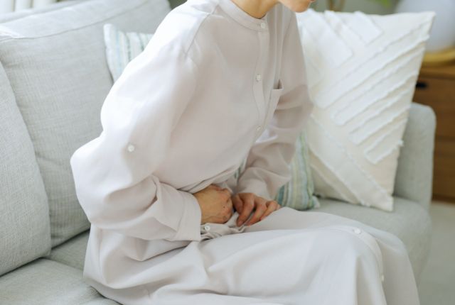 お腹に手をあて辛そうにしている女性