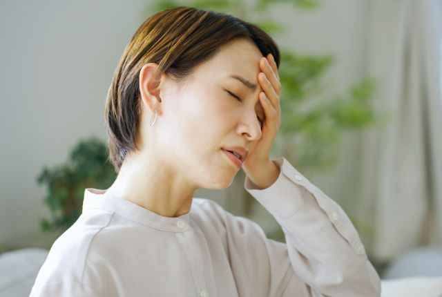 額に手を当て辛そうにしている女性